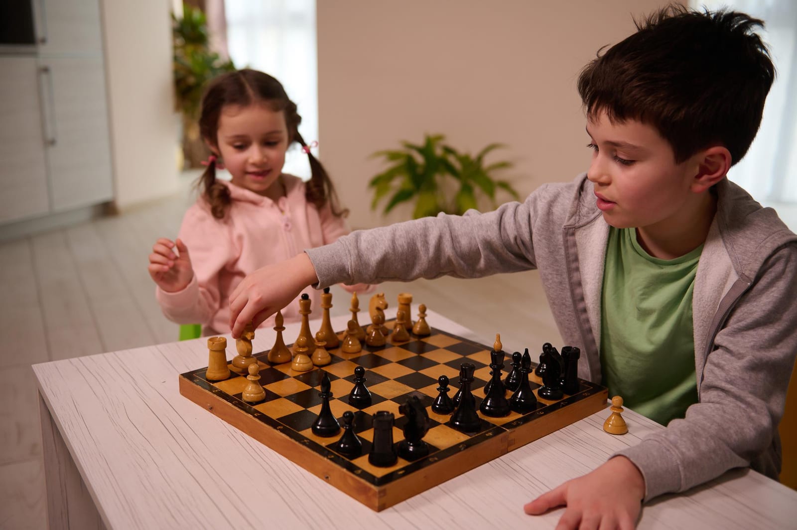Duas crianças jogando xadrez em casa, atividade de programa escolar